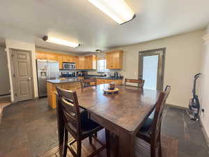 Dining area with stone tile flooring, a textured ceiling, and baseboards