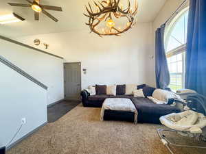 Carpeted living area with ceiling fan with notable chandelier