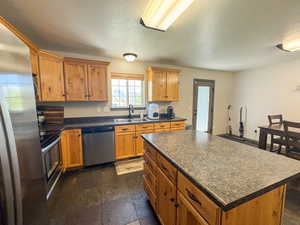 Kitchen with a sink, a textured ceiling, dark countertops, and stainless steel appliances