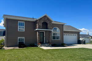 Traditional-style house featuring a garage, a front lawn, fence, roof with shingles, and driveway