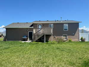 Rear view of house with fence, a yard, stairway, and a deck