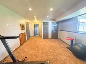 Workout area with recessed lighting, a textured ceiling, baseboards, and light colored carpet
