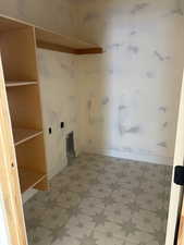 Clothes washing area featuring baseboards and light floors