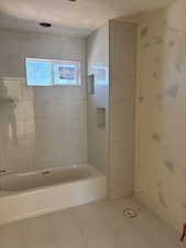 Full bath with a textured ceiling and shower / washtub combination