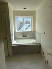 Bathroom with a textured ceiling, tile patterned flooring, and a bath