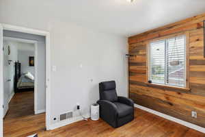 Bedroom with visible vents, wood walls, and wood finished floors