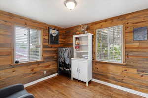 Bedroom featuring wood walls, wood finished floors, and a wealth of natural light