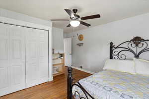 Bedroom featuring visible vents, a closet, wood finished floors, baseboards, and ceiling fan