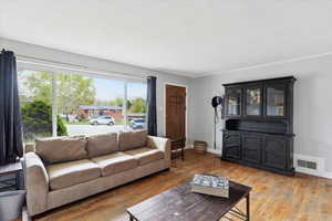 Living room featuring a textured ceiling, baseboards, wood finished floors, and visible vents