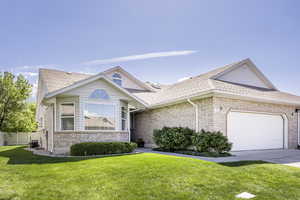 View of front facade featuring brick siding, an attached garage, a front yard, and roof with shingles