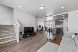 Living area featuring recessed lighting, dark wood-style floors, and stairway