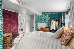 Bedroom featuring cooling unit, wallpapered walls, and wood finished floors