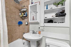 Bathroom featuring a sink, toilet, and shower / tub combo with curtain