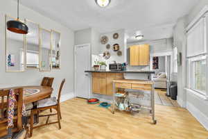 Kitchen with light brown cabinetry, baseboards, stainless steel microwave, and light wood-style flooring