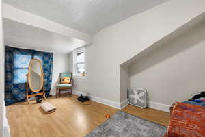 Sitting room featuring a textured ceiling, baseboards, and wood finished floors