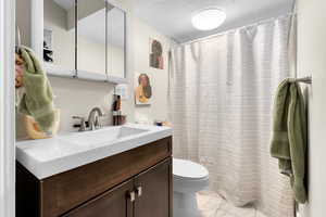 Full bathroom featuring vanity, marble finish floor, toilet, and a shower with curtain