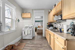 Kitchen featuring a sink, light brown cabinets, white range with gas stovetop, and dark wood-style flooring
