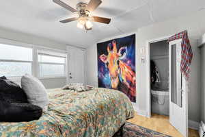 Bedroom with a baseboard radiator, ceiling fan, wood finished floors, and lofted ceiling