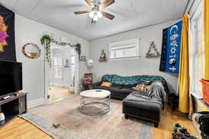 Living area with a ceiling fan, wood finished floors, and a wealth of natural light