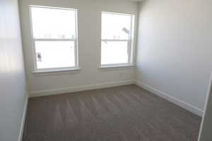 Carpeted spare room featuring baseboards
