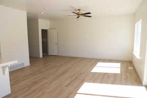 Empty room featuring baseboards, ceiling fan, visible vents, and light wood-style flooring