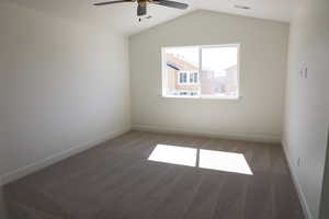 Unfurnished room featuring carpet floors, baseboards, ceiling fan, and lofted ceiling