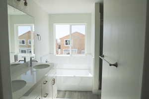 Full bathroom featuring a wealth of natural light, a sink, and wood finished floors