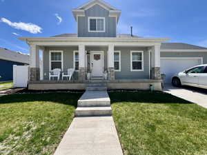 View of front of property featuring an attached garage, a front lawn, board and batten siding, a porch, and driveway