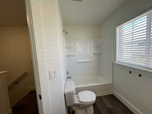 Full bathroom with toilet, baseboards, shower / bath combination, wood finished floors, and visible vents