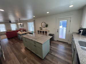 Kitchen with recessed lighting, dark wood-style flooring, a healthy amount of sunlight, and a center island