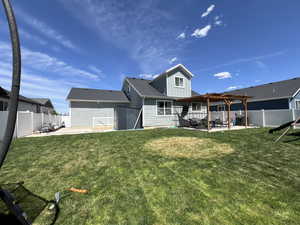 Rear view of house with a pergola, board and batten siding, a fenced backyard, a lawn, and a patio