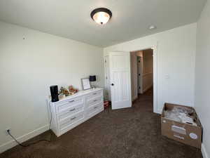 Bedroom featuring baseboards and dark carpet
