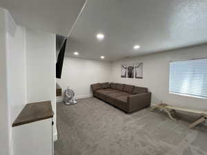 Living room featuring baseboards, carpet, recessed lighting, and a textured ceiling