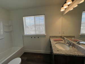 Bathroom with vanity, baseboards, toilet, and wood finished floors
