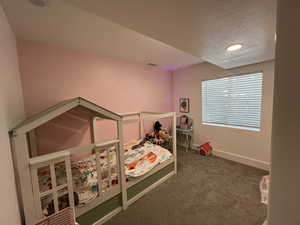 Carpeted bedroom with baseboards, a textured ceiling, and visible vents