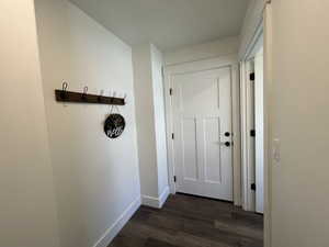 Garage Doorway featuring baseboards and dark wood finished floors