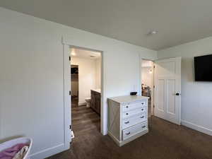 Primary Bedroom featuring baseboards and dark colored carpet