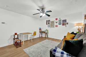 Sitting room featuring light wood-style floors, a ceiling fan, and baseboards