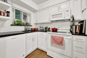 Kitchen featuring a sink, white cabinets, white appliances, and tasteful backsplash