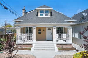 View of front of property featuring a porch, roof with shingles, fence, and a chimney