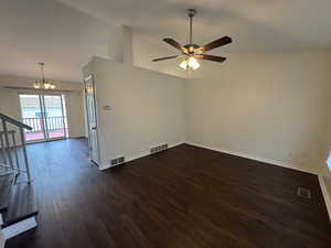 Unfurnished room featuring visible vents, dark wood finished floors, and ceiling fan with notable chandelier
