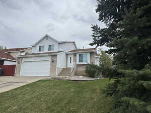 View of front of house featuring a garage, a front yard, driveway, and brick siding