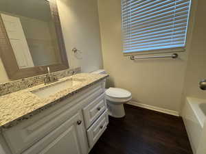 Full bath with vanity, toilet, a bathtub, baseboards, and wood finished floors