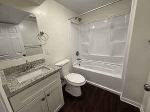 Bathroom featuring vanity, shower / tub combination, wood finished floors, and toilet