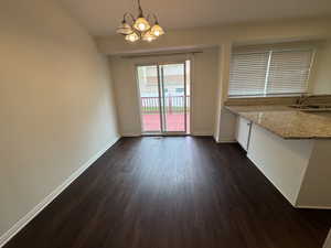 Unfurnished dining area featuring baseboards, a chandelier, dark wood-style floors, and a sink