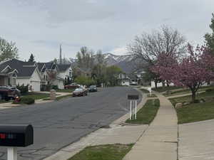 View of street with a residential view, sidewalks, a mountain view, and curbs
