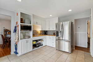 Kitchen featuring light countertops, white cabinetry, open shelves, and appliances with stainless steel finishes