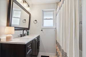 Bathroom featuring a healthy amount of sunlight, baseboards, and vanity
