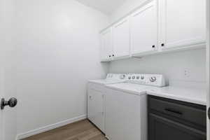 Laundry room with baseboards, washer and clothes dryer, cabinet space, and light wood finished floors