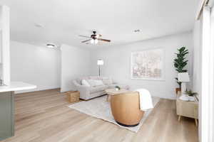 Living room with baseboards, a ceiling fan, light wood-style flooring, and visible vents